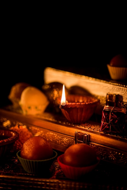 Diwali diya or lighting in the night with gifts, flowers over moody scene