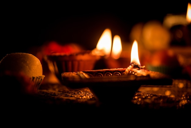 Diwali diya or lighting in the night with gifts, flowers over moody scene