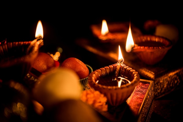 Diwali diya or lighting in the night with gifts, flowers over moody scene