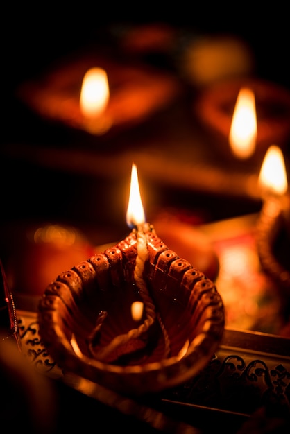 Diwali diya or lighting in the night with gifts, flowers over moody scene