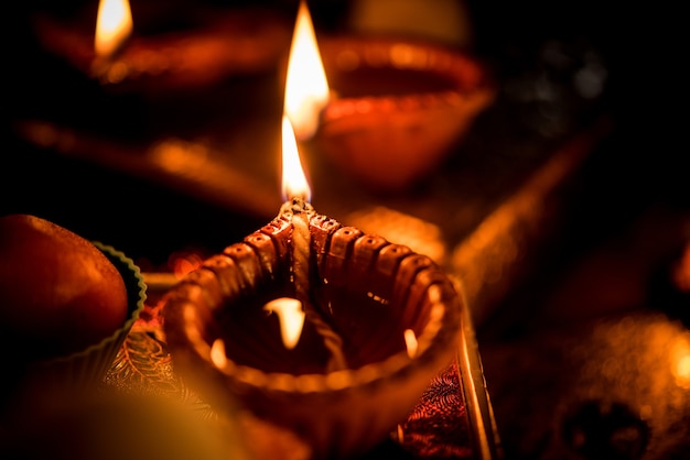 Diwali diya or lighting in the night with gifts, flowers over moody scene