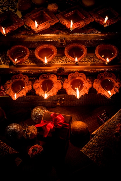 Diwali diya or lighting in the night with gifts, flowers over moody scene