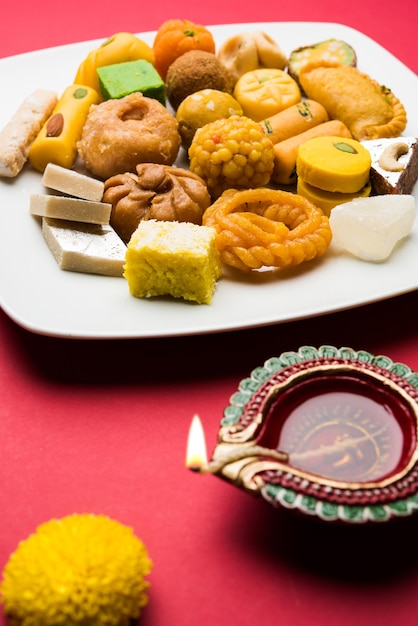 Diwali Diya, Sweets OR Mithai and Gift boxes arranged over decorative background. Selective focus