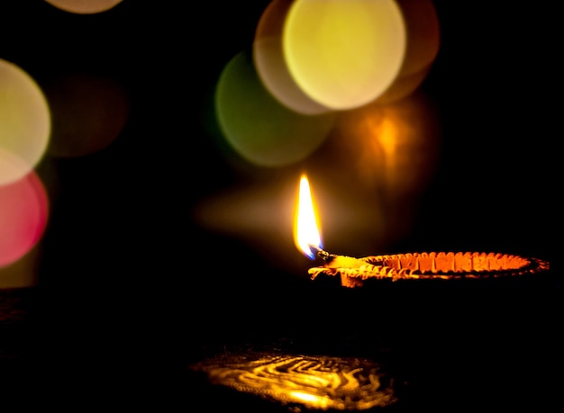 Diwali, hindoeïstisch lichtfeest. Klei diya kaars verlicht in Deepawali. Traditionele olielamp op donkere achtergrond, kopieer ruimte.