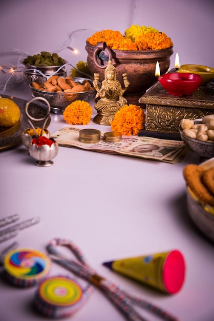 Diwali and preparation for Laxmi or Lakshmi Pooja with elements like diya, currency notes, sweets, flowers, snacks, haldi and kumkum