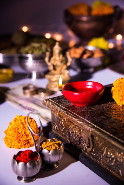 Diwali and preparation for Laxmi or Lakshmi Pooja with elements like diya, currency notes, sweets, flowers, snacks, haldi and kumkum