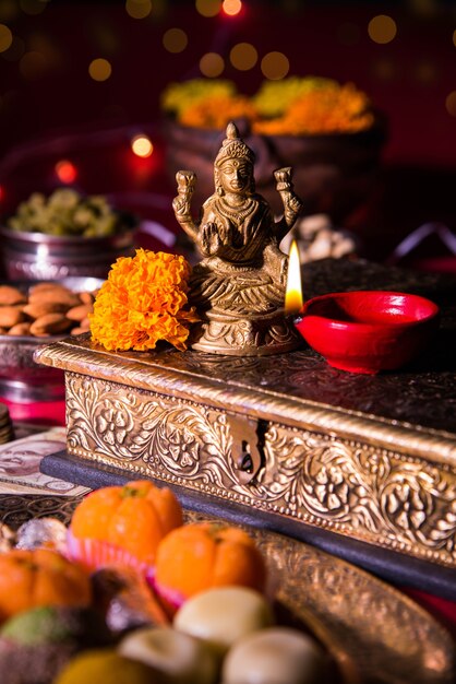 Diwali and preparation for Laxmi or Lakshmi Pooja with elements like diya, currency notes, sweets, flowers, snacks, haldi and kumkum