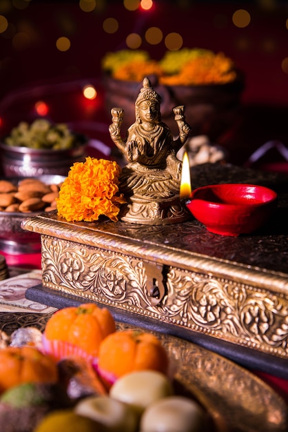 Photo diwali and preparation for laxmi or lakshmi pooja with elements like diya, currency notes, sweets, flowers, snacks, haldi and kumkum