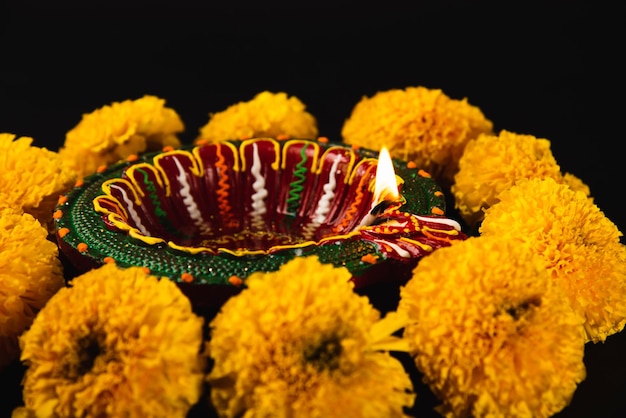 Photo diwali's charm captured a radiant diwali lamp and ornate flower rangoli on a striking black background perfect for festive invitations ceremonies and celebrations
