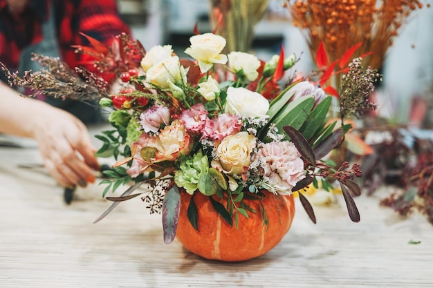 DIY autumn flower arrangement bouquet in pumpkin florist at the work floristry studio