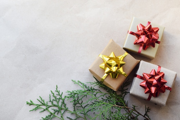 Рождественские подарочные коробки с бантиками своими руками в домашних условиях. Коробки с подарками на фоне крафт-бумаги и ветки ели