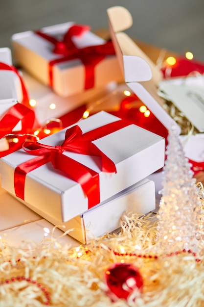 DIY Christmas present wrapping Christmas gift white box with a red ribbon, festive decoration on the table.