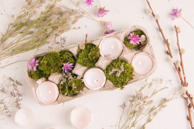 Diy for easter. shell from eggs with candles on a white background with field flowers