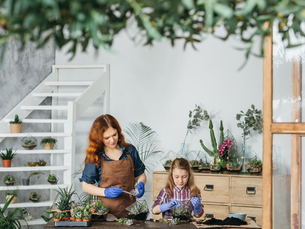 DIY florarium. Creative family hobby and leisure. Mother and daughter working with succulents at their indoor garden.