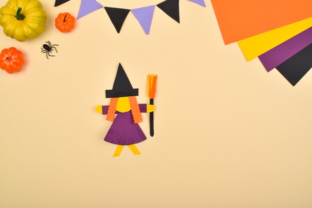 DIY Halloween. We make a witch out of colored paper. Step-by-step instructions. Step 10: Glue the broom to the witch.