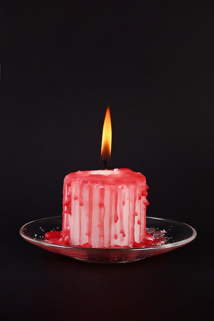 Diy Halloween white candle covered in red wax like blood drops on black background