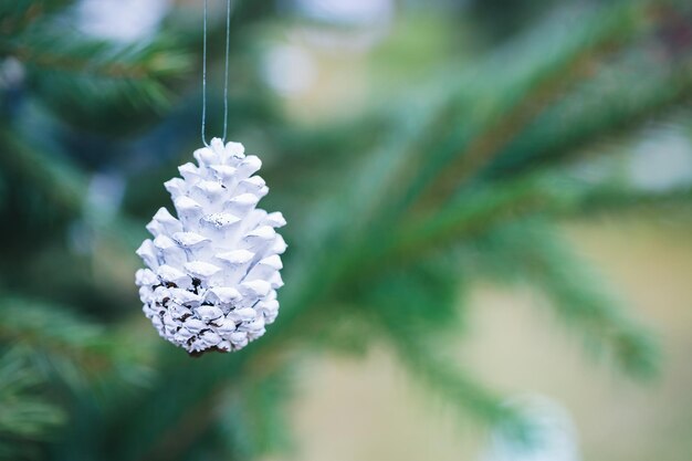 DIY handgemaakte decoratie op kerstboom Wit geschilderde dennenappel
