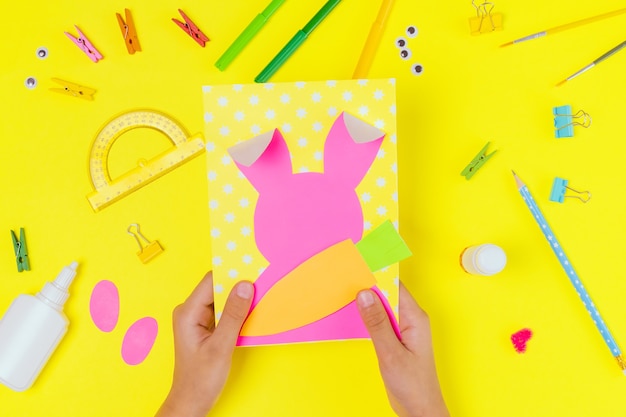 DIY and kids creativity. Step by step instruction: Create an Easter card with bunny and carrot. Childrens handmade Easter craft. Top view Step 3