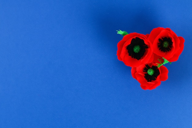 Photo diy paper red poppy anzac day, remembrance, remember, memorial day crepe paper on blue background.