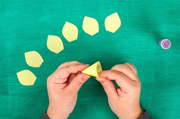 Foto la molla di diy fiorisce i narcisi di carta gialla su un fondo verde.