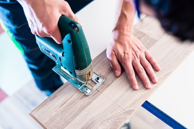 DIY worker cutting wooden panel with jigsaw