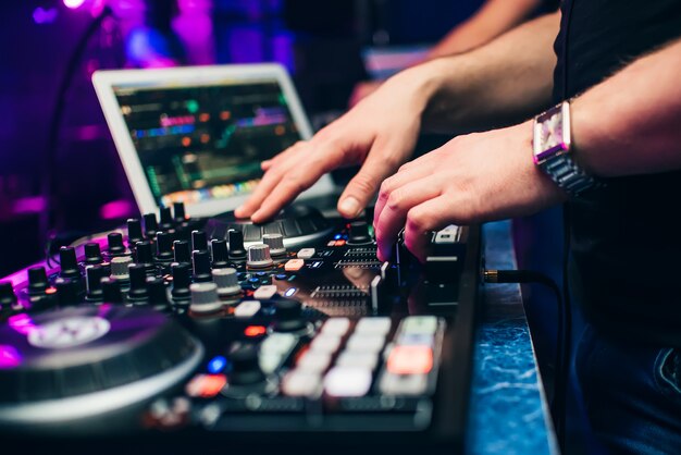 Dj in a booth playing a mixer at a nightclub