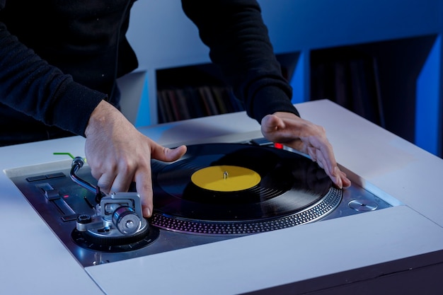 Foto dj colocando un disco de vinilo en su tocadiscos mientras mezcla msica en una tienda de discos