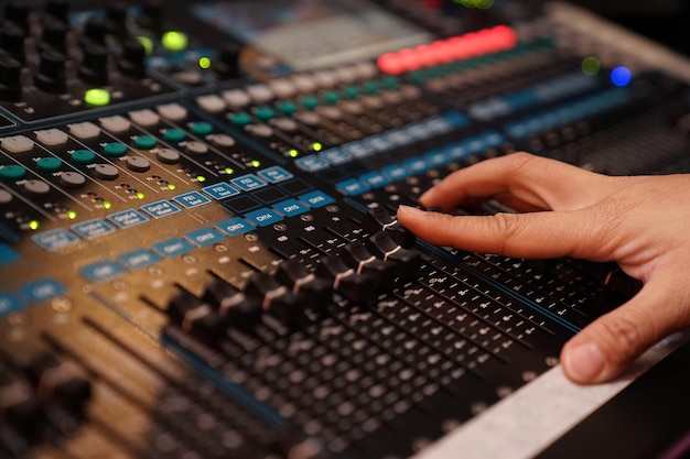 Dj controles sound controller and plays mixed edm music in the concert nightclub at a party