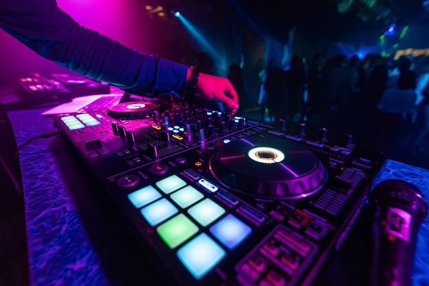 DJ hand plays a professional mixer at a nightclub