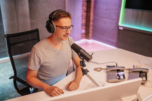 The dj hosts the program and communicates with the audience on
air at the radio station. the announcer reads the news. a male
radio host speaks into a microphone and records a podcast