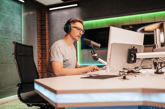 The dj hosts the program and communicates with the audience on\
air at the radio station the announcer reads the news a male radio\
host speaks into a microphone and records a podcast