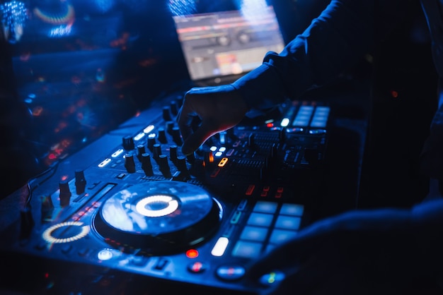 DJ in een stand die een mixer speelt in een nachtclub