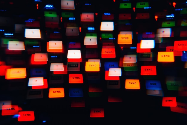 DJ mixer in a nightclub with glowing colored lights from controllers and buttons