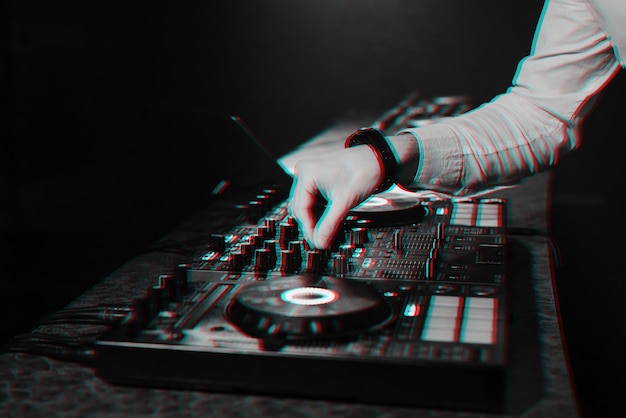 Ди-джей микширует электронную музыку руками на пульте управления музыкой в ночном клубе в кабинке. черно-белый с эффектом виртуальной реальности 3d глюк