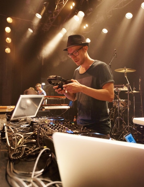 DJ muziek en schijnwerpers op de man op het podium met koptelefoon en apparatuur voor optreden op soundboard Techno muzikant en persoon in de club's nachts mixen op draaitafel met technologie voor rave