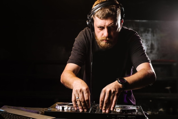 DJ plays on a mixer in the club on black background