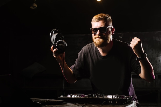 DJ plays on a mixer in the club on black background