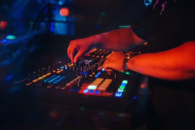 DJ plays on music mixer in a nightclub