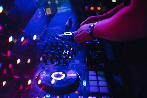 DJ speelt op muziekmixer in een nachtclub