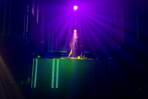 DJ on stage in disco night club mixing techno music beat