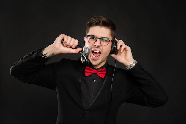 DJ with headphones and microphone on a black wall