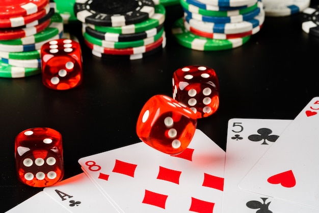 Dobbelstenen en chips op zwarte tafel close-up