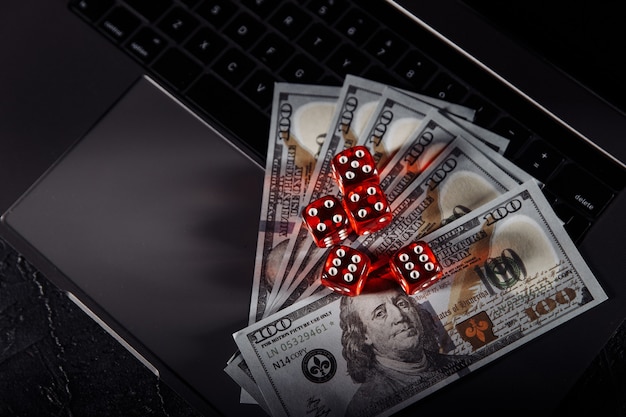 Dobbelstenen en dollarbankbiljetten op het toetsenbord van de laptop. Online casino en gokken concept