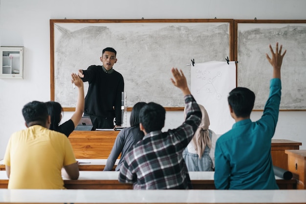 Docent wijst naar een student met een opgeheven hand in de klas Studenten die hun handen opheffen met een vraag