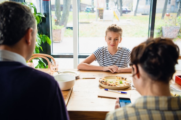 Dochter chatten met haar ouders aan de tafel