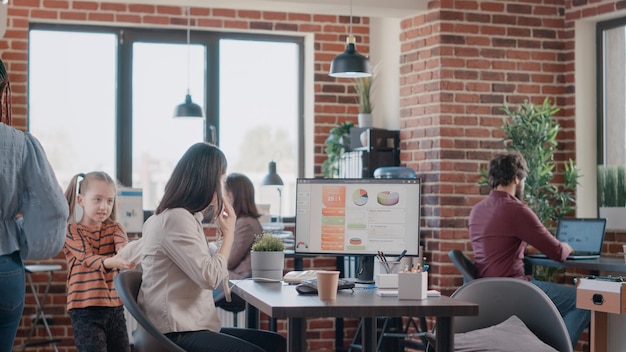 Dochter die alleenstaande moeder verontrust met belangrijke oproep op vaste telefoon op het werk. Klein meisje onderbreekt werkende moeder met telefoon, probeert een discussie te voeren over het project.