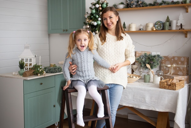 Dochter en moeder die op Kerstmisachtergrond koesteren