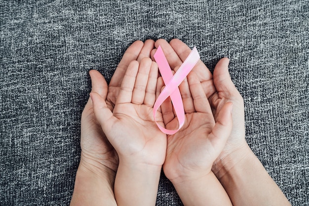Dochter- en moeders handen met het roze kankerlint op hun handpalmen