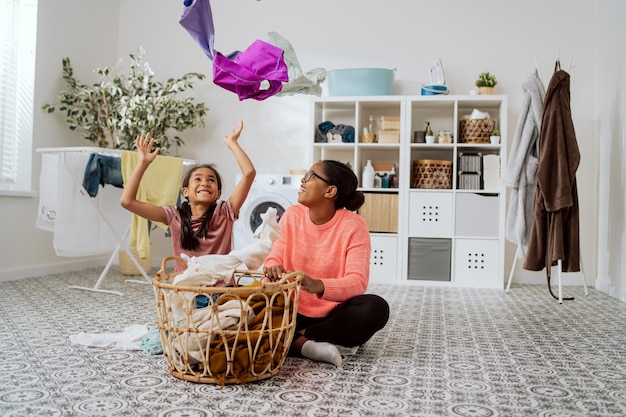 Dochter is aan het spelen door moeder die haar kleren hoog boven haar hoofd gooit