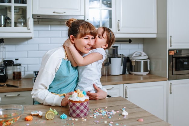 Dochter kussende moeder op het moment van het koken van Pasen cake